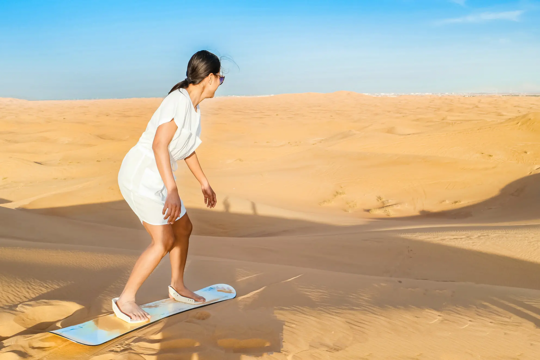 Kobieta próbująca sandboardingu na pustyni