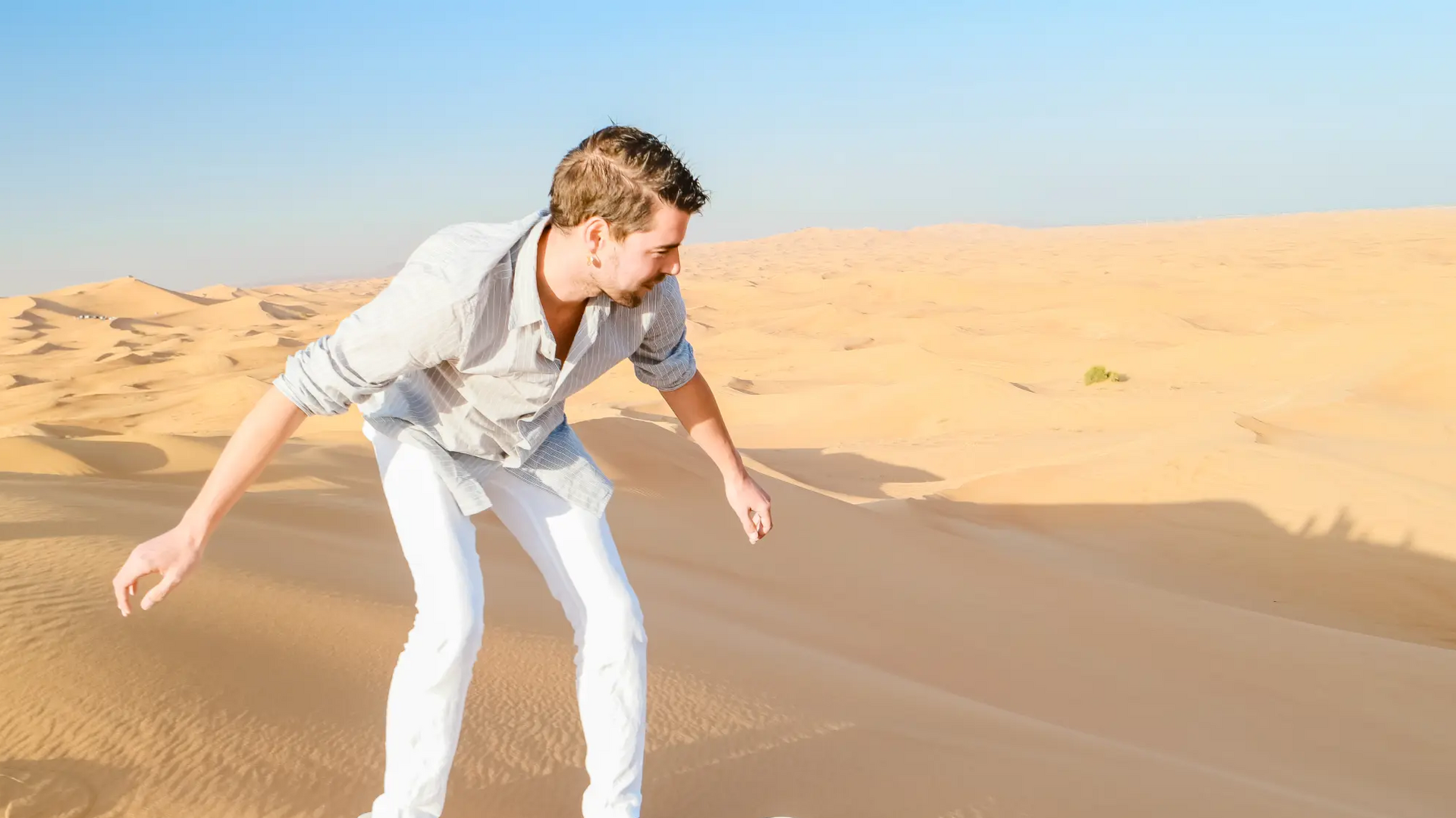 Mężczyzna trenujący sandboarding na pustyni