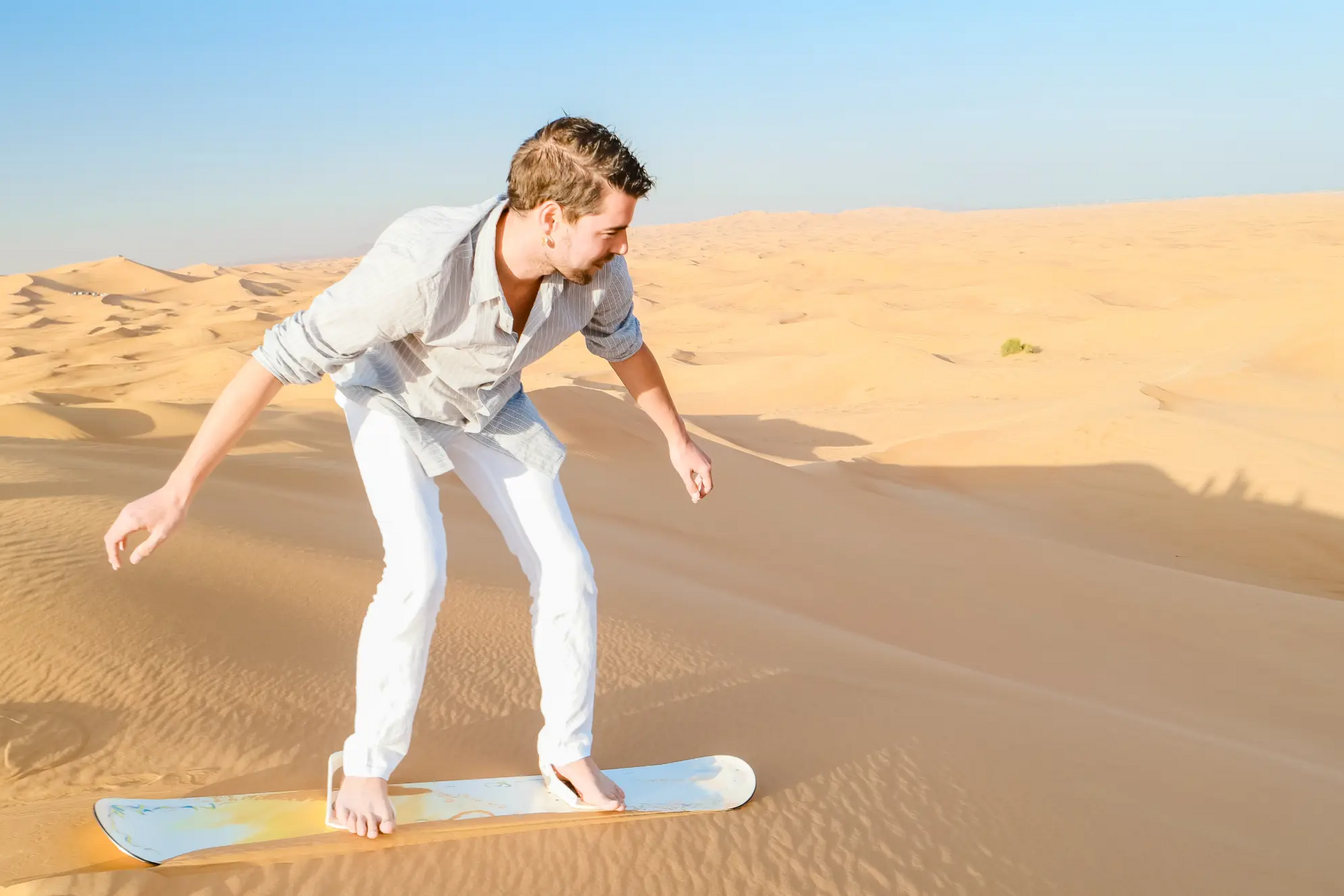 Mężczyzna trenujący sandboarding na pustyni