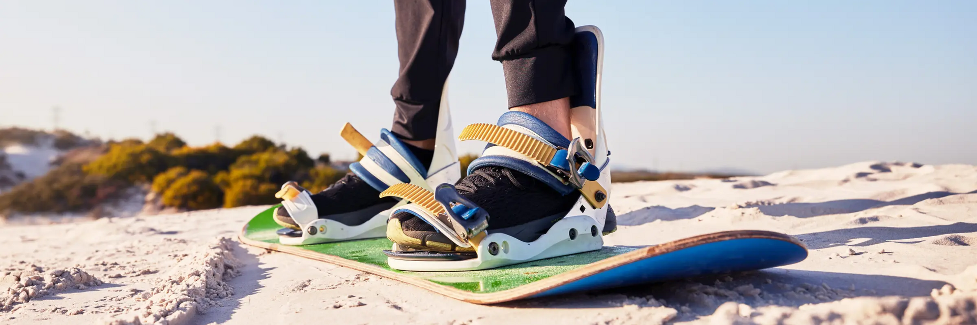 Mężczyzna ćwiczący sandboarding stojoący na desce na pustyni