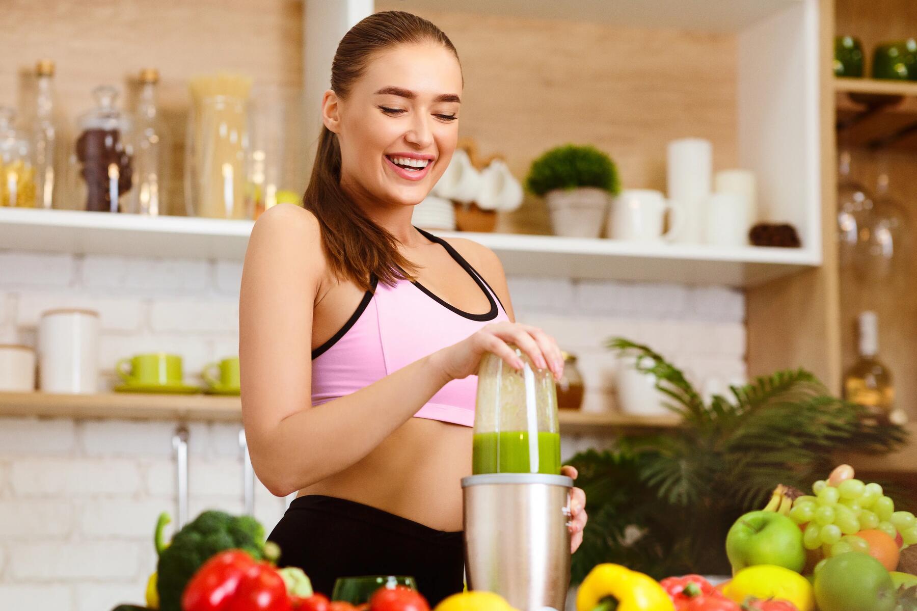 Kobieta w stroju sportowym przygotowująca smoothie w kuchni