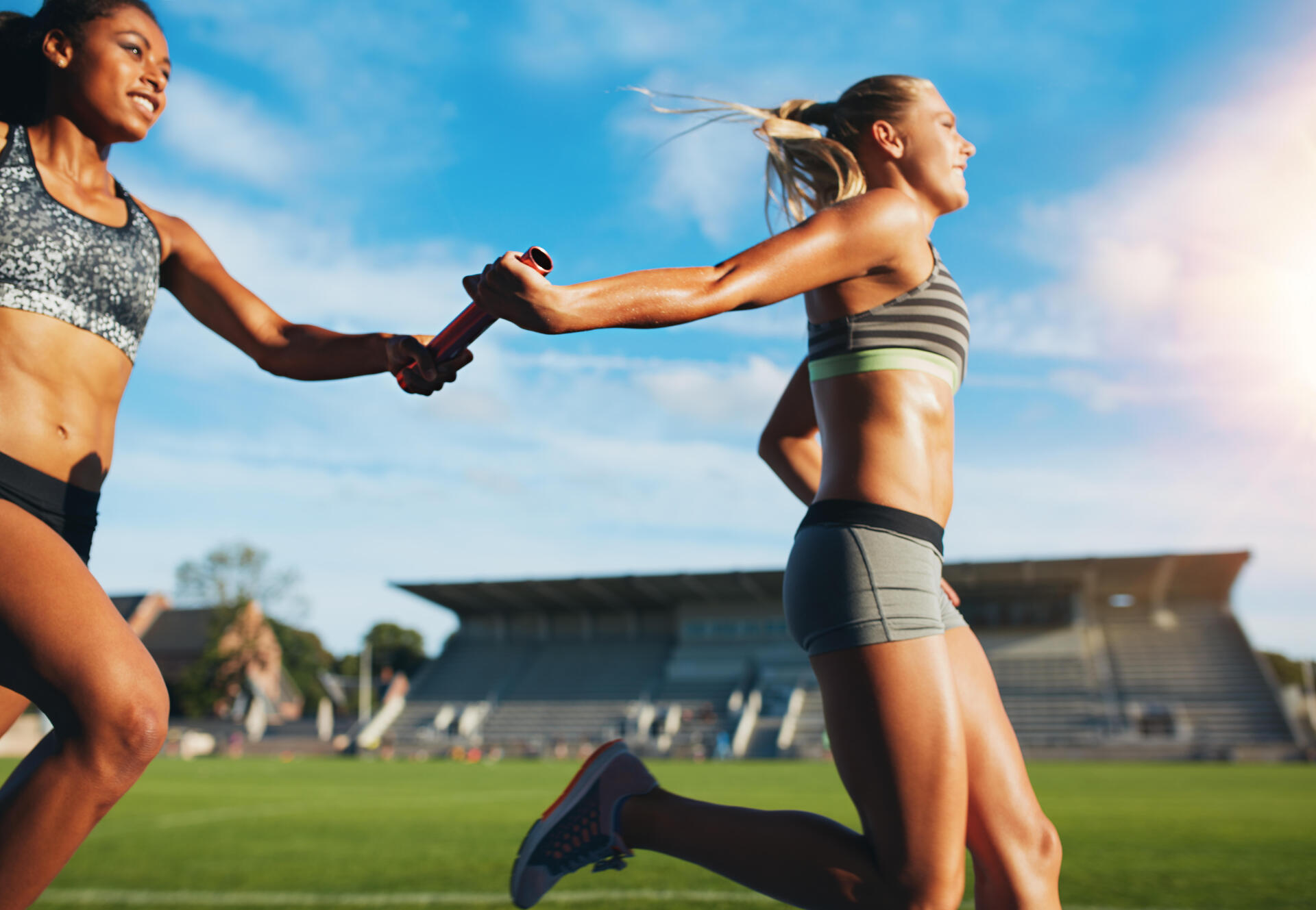 Kobiety w strojach sportowych biegnące w sztafecie