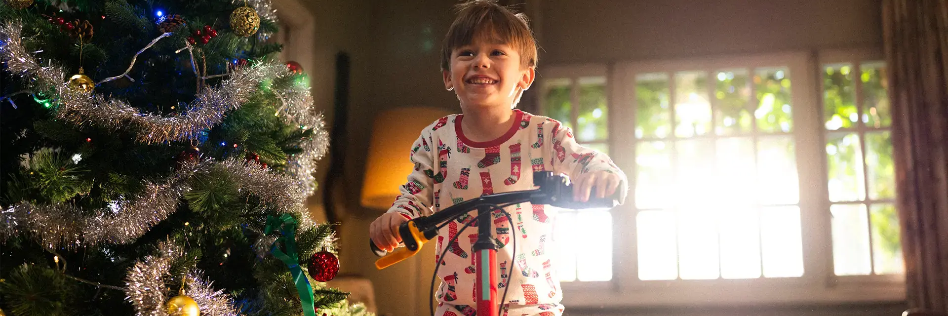 kid on a bike next to a Christmas tree