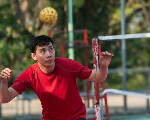 Chłopak odbijający piłkę głową grający w sepak takraw