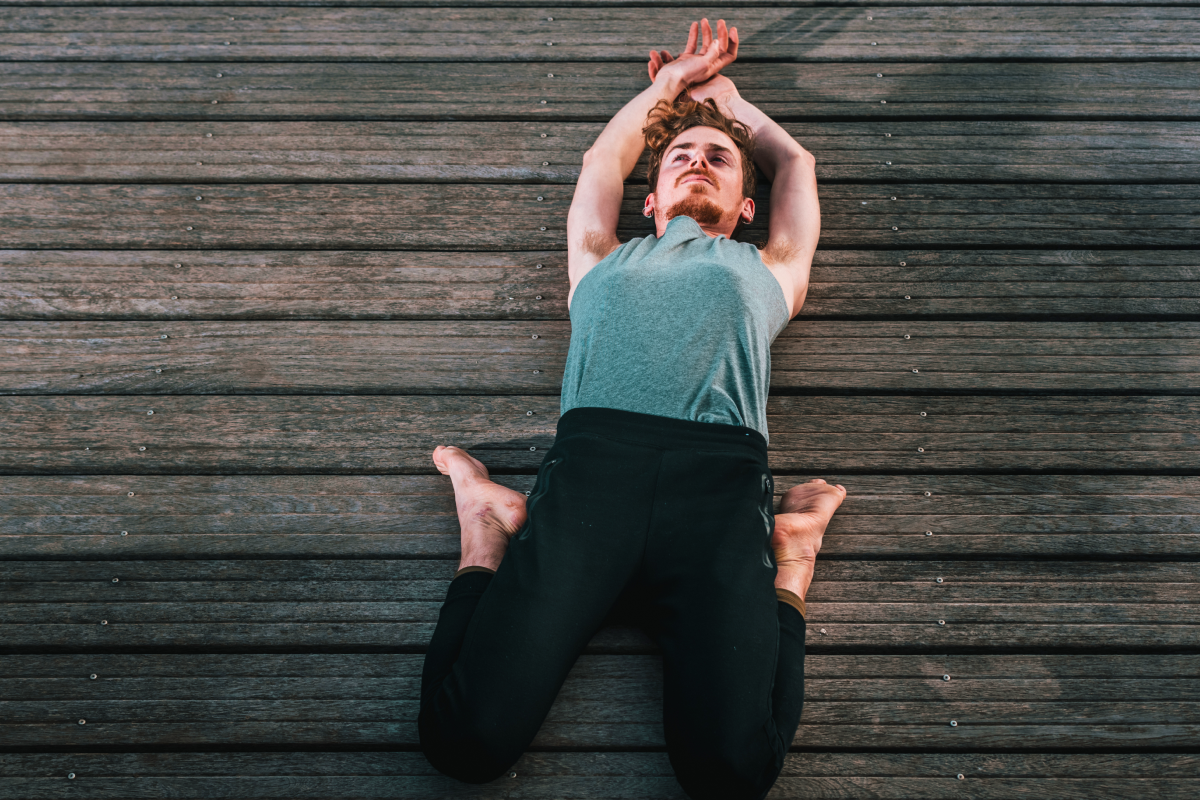 Mężczyzna leżący na pomoście w pozycji supta virasana