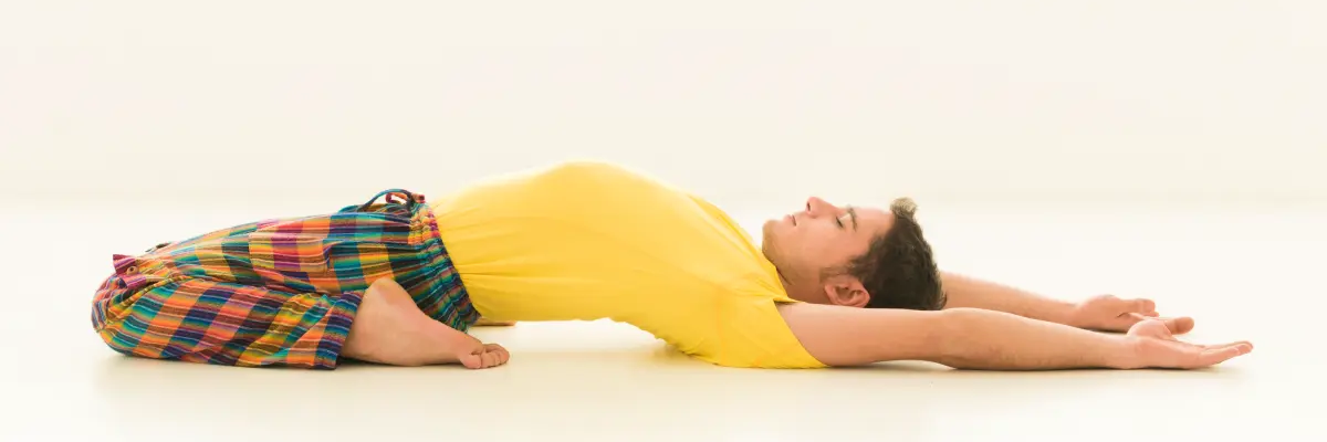 Mężczyzna leżący na ziemi w pozycji supta virasana