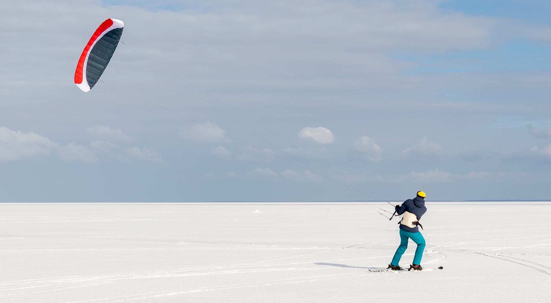 Osoba uprawiająca kitesurfing z latawcem na śniegu