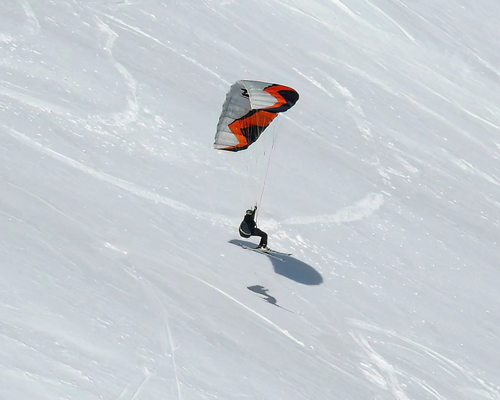 Osoba uprawiająca snowkite czyli kitesurfing z latawcem na śniegu