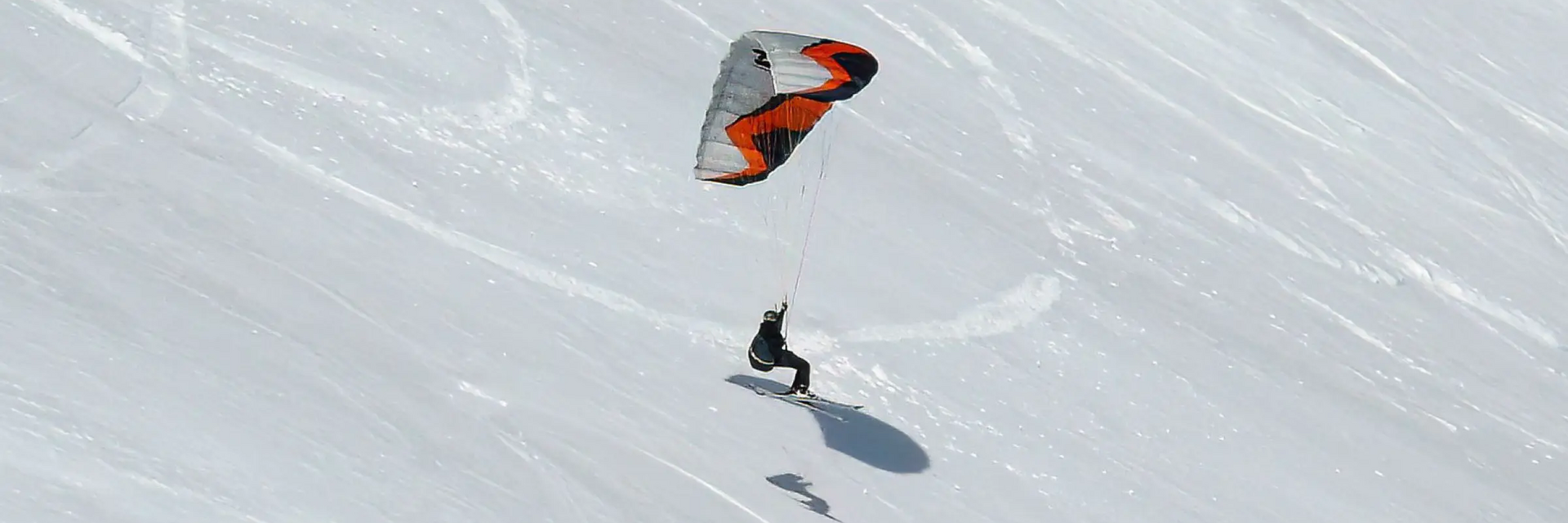 Osoba uprawiająca snowkite czyli kitesurfing z latawcem na śniegu