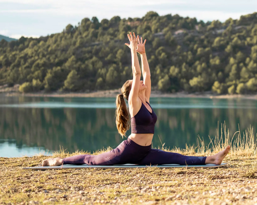 Kobieta ćwicząca hanumanasana w jodze na macie w plenerze