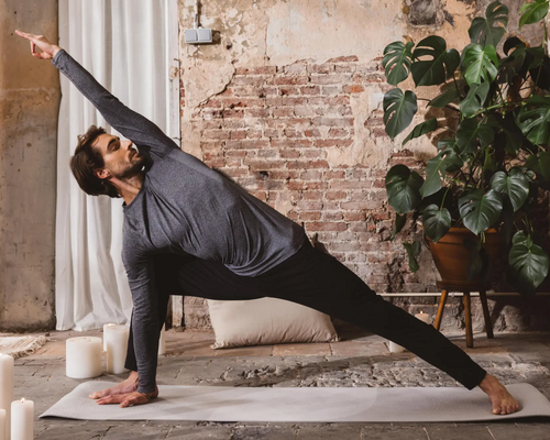 Mężczyzna w odzieży sportowej ćwiczący na macie pozycję utthita parsvakonasana w jodze