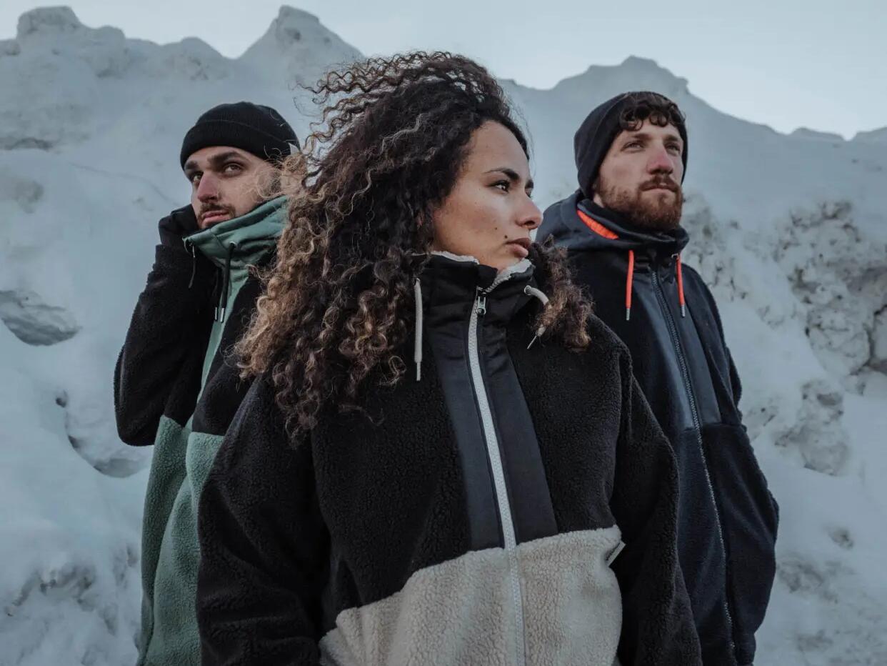 2 men and a woman looking into the mountain with a snowed mountain in the background.