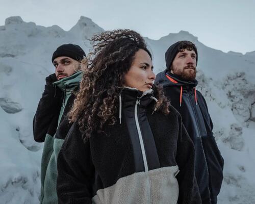 2 men and a woman looking into the mountain with a snowed mountain in the background.