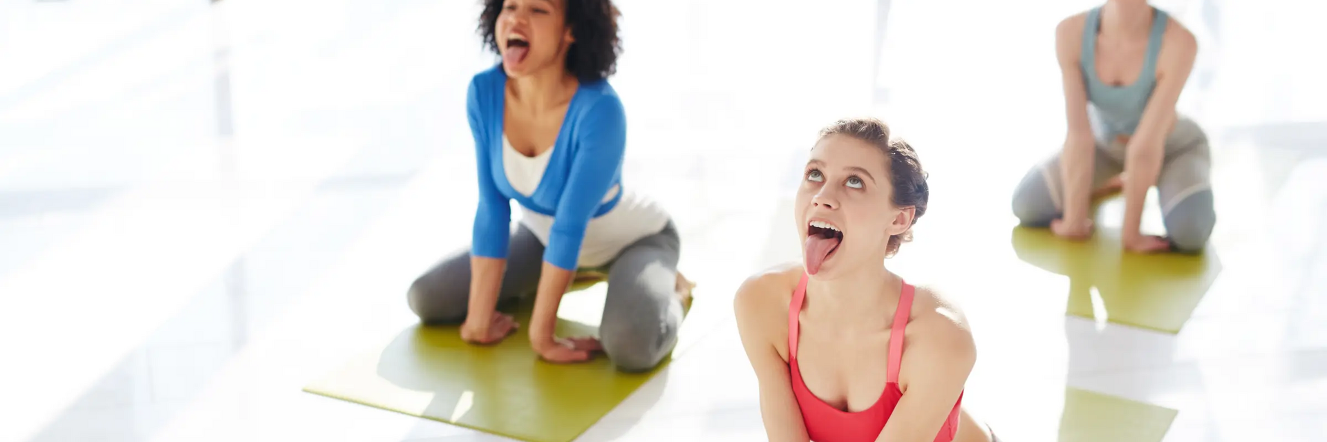 Kobiety w odzieży sportowej siedzące na matach w pozycji simhasana w jodze