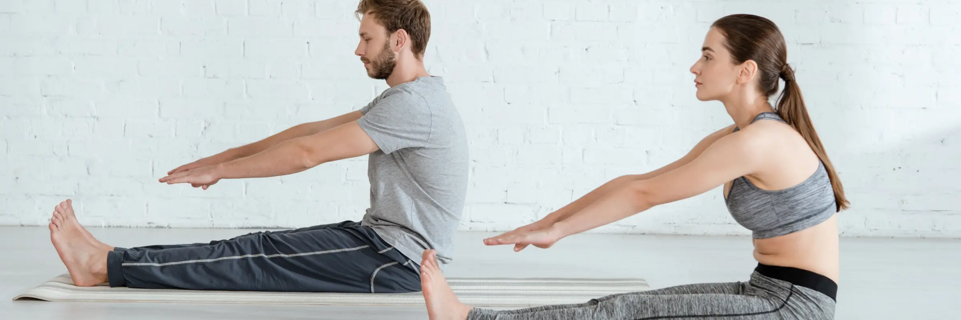 Para siedząca na matach w odzieży sportowej ćwicząca dandasana w jodze