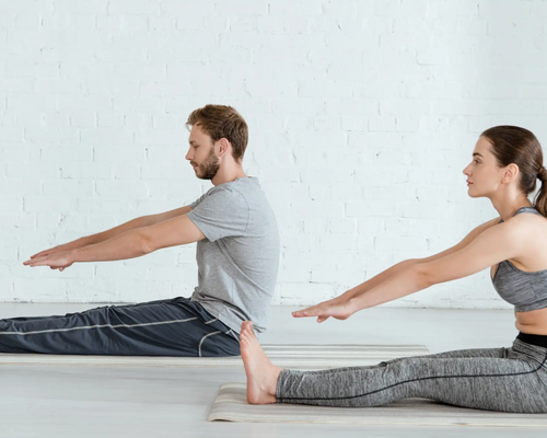 Para siedząca na matach w odzieży sportowej ćwicząca dandasana w jodze