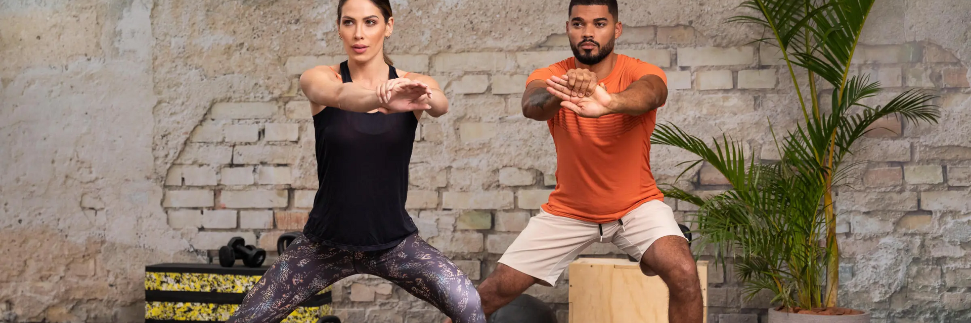 Ludzie w strojach sportowych ćwiczący wykrok w bok z wyciągniętymi przed siebie złączonymi rękami