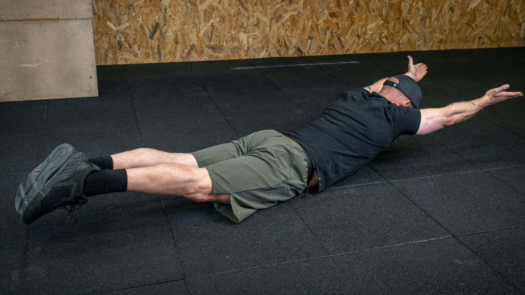 Mężczyzna wykonujący na podłodze ćwiczenie arch body hold