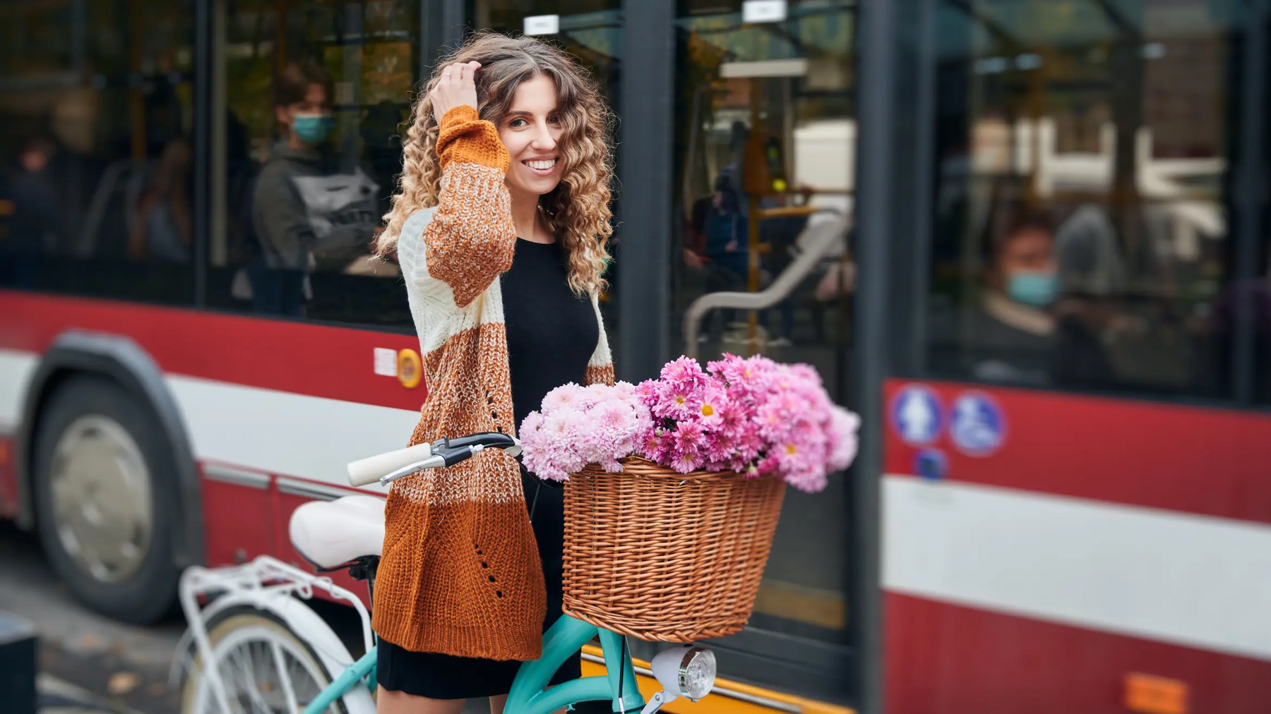 Kobieta stojąca na rowerze obok niej autobus