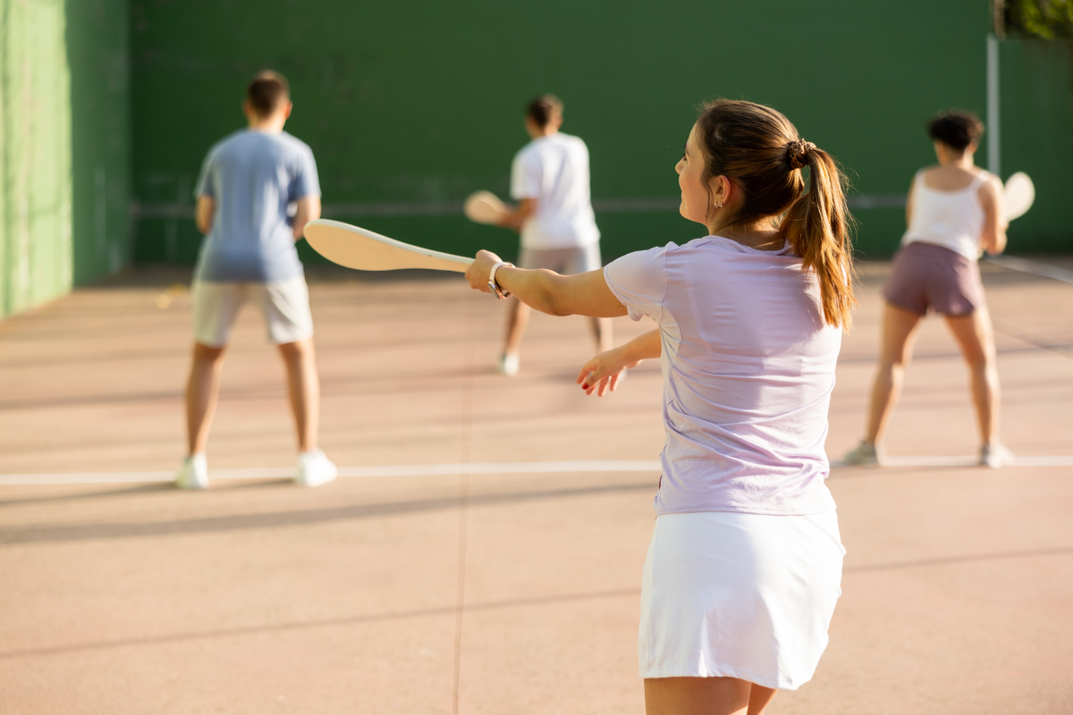Kobieta w odzieży sportowej stojąca na korcie trzymająca rakietę w dłoni