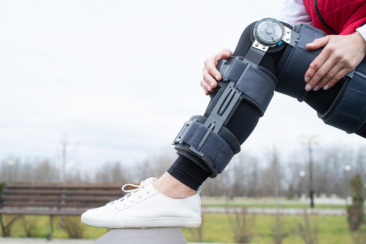 Osoba poprawiająca zawiasowy stabilizator na kolanie