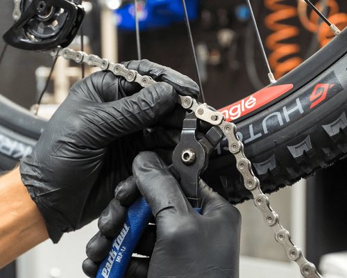 Man undoing a bike chain with chain break tool