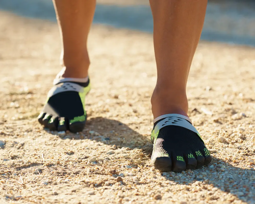 Osoba chodząca po piasku w butach barefoot