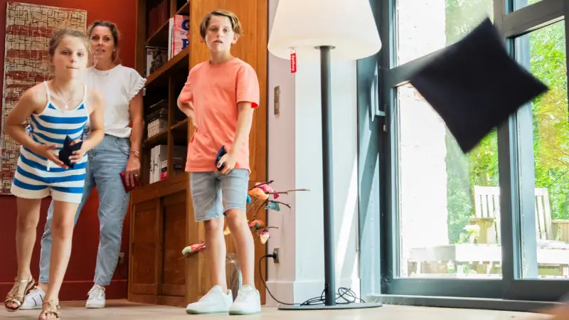 Een gezin van drie speelt binnenshuis cornhole