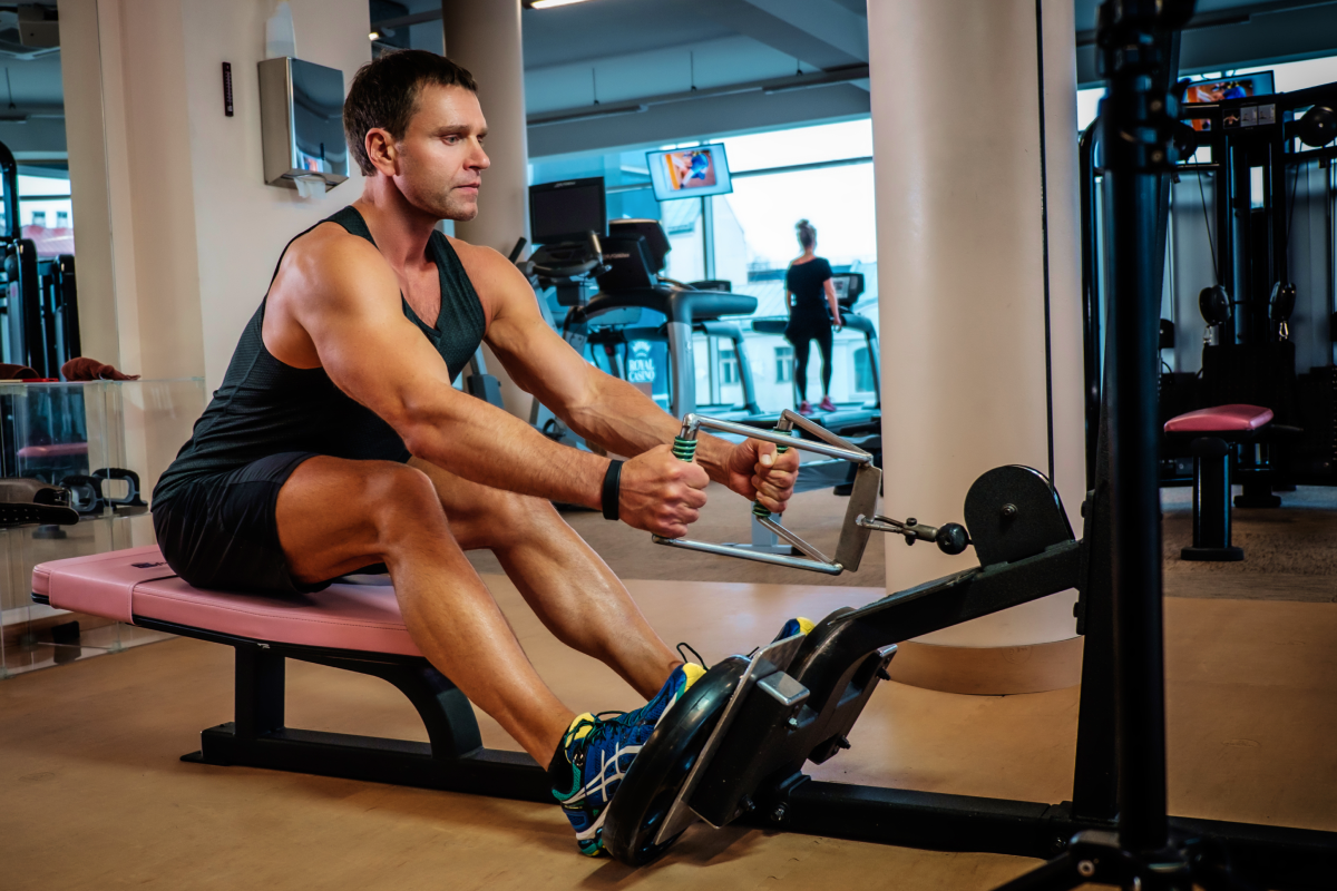 Mężczyzna w odzieży sportowej ćwiczący wiosłowanie na wyciągu dolnym