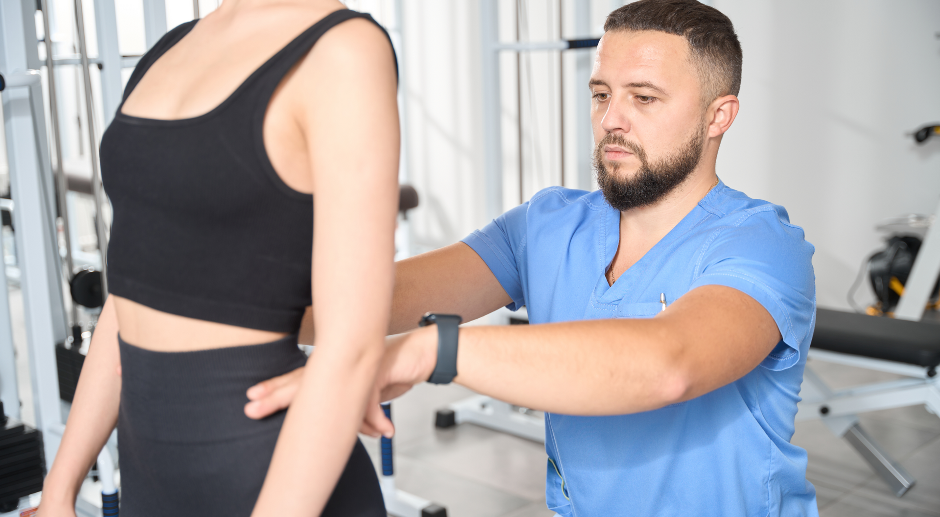 Fizjoterapeuta dotykający talii kobiety stojącej do niego tyłem