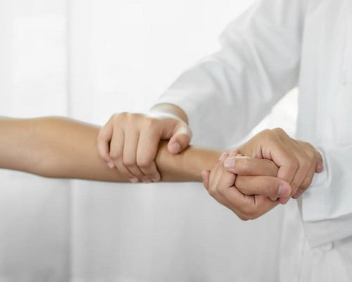 Fizjoterapeuta trzymający kobietę za dłoń drugą rękę trzyma na nadgarstku