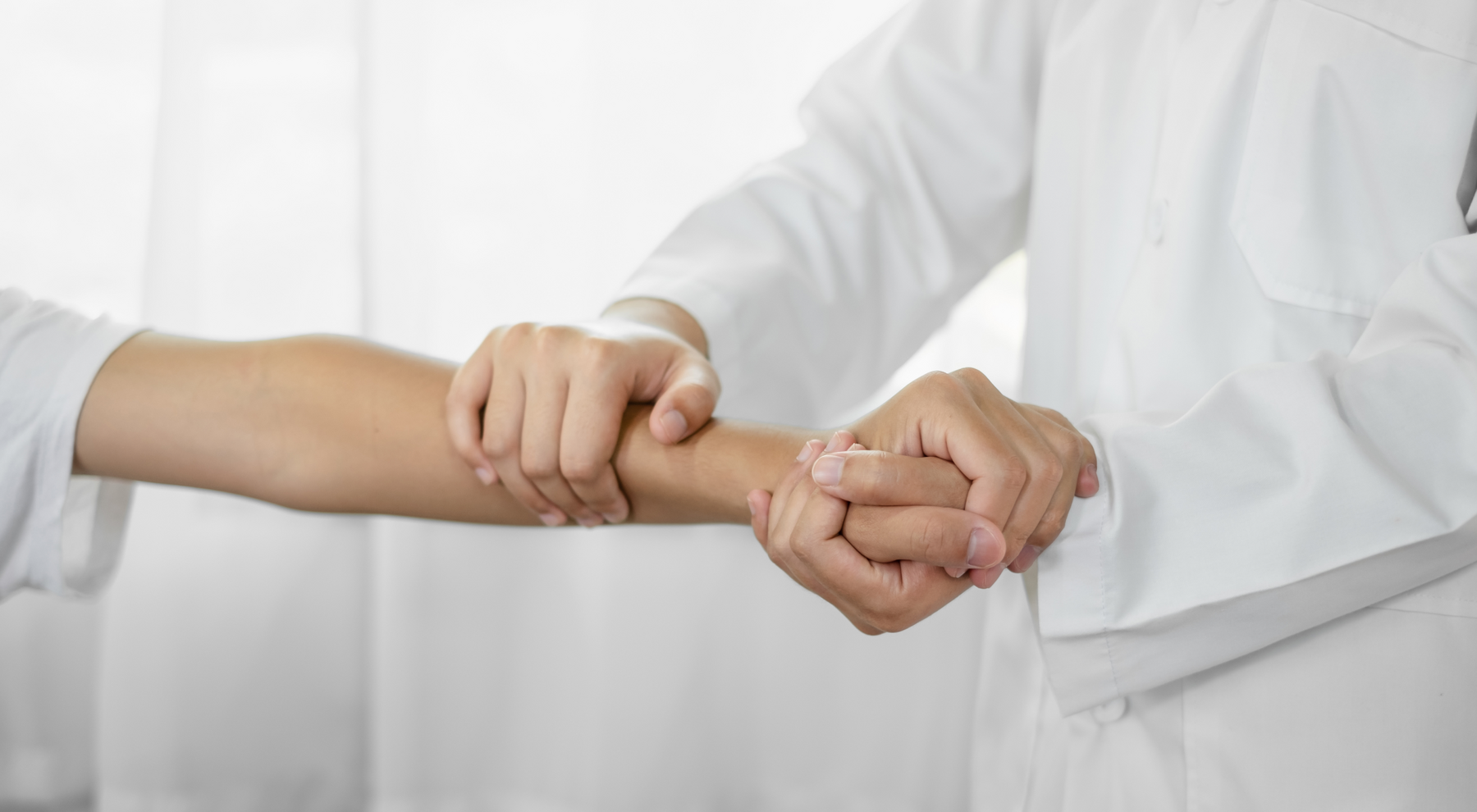 Fizjoterapeuta trzymający wyprostowaną rękę kobiety za dłoń i za nadgarstek
