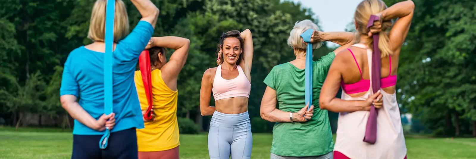 Kobiety w odzieży sportowej ćwiczące z gumą trzymające gumę w rękach za plecami