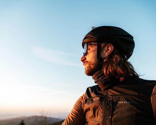 Man cycling in greenery, wearing a black cycling cap.