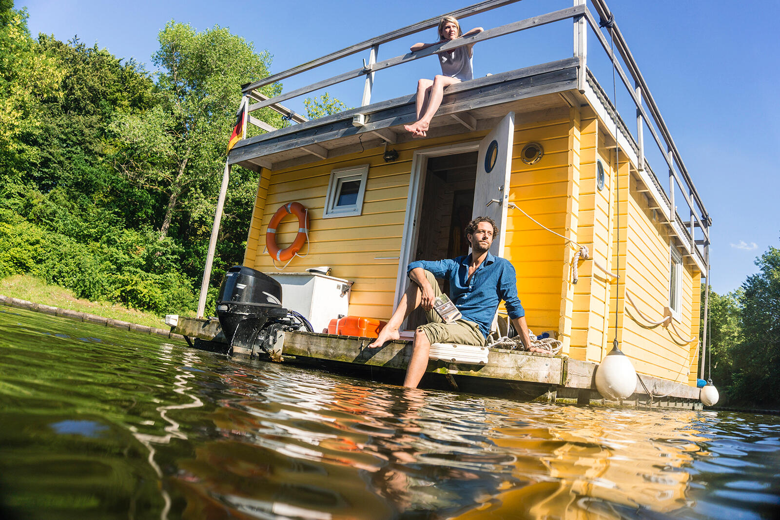 Mężczyzna siedzący i moczący nogę z houseboatu