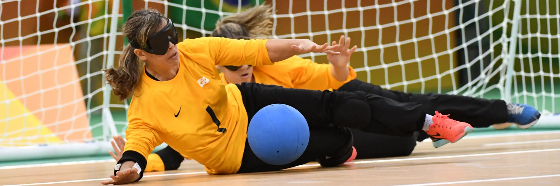 Kobiety z opaskami na oczach grające na sali w torball