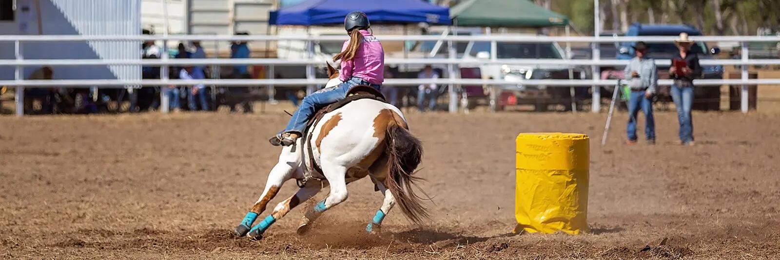 Kobieta w kasku na koniu biorąca udział w barrel racing