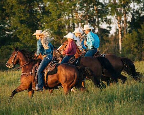 Ludzie w kapeluszach jadący na koniach w stylu western riding