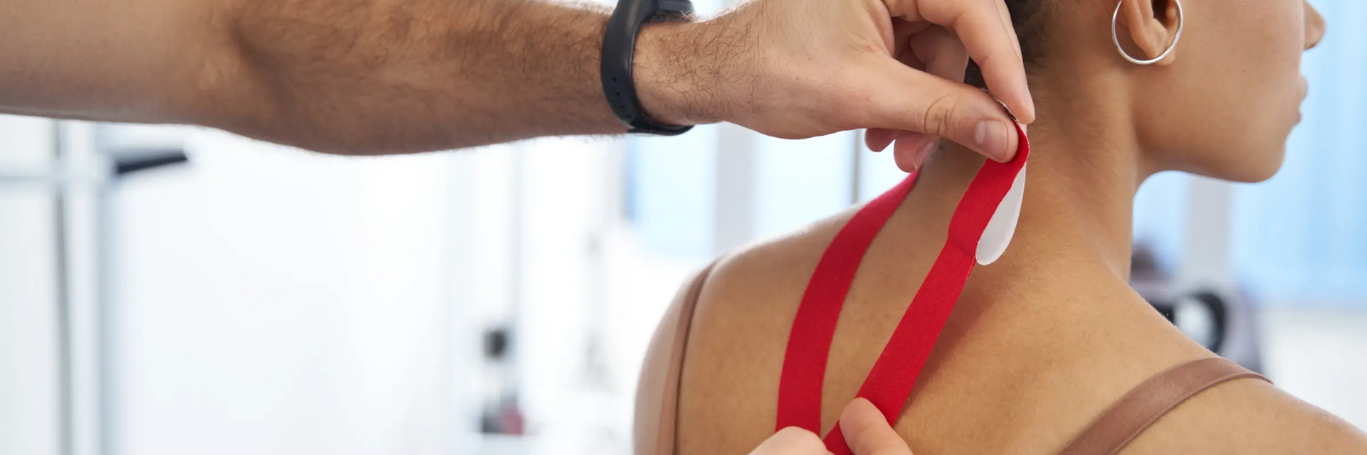 Mężczyzna naklejający taśmy kinezjologiczne kobiecie na kark