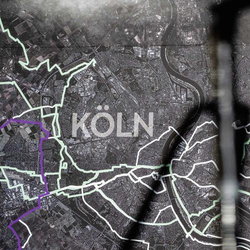 Dunkle Stadtkarte mit weißen Linien, violetten Akzenten und großem „Köln“-Schriftzug in der Mitte.