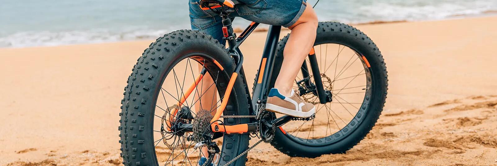 Mężczyzna stojący na fatbike na plaży
