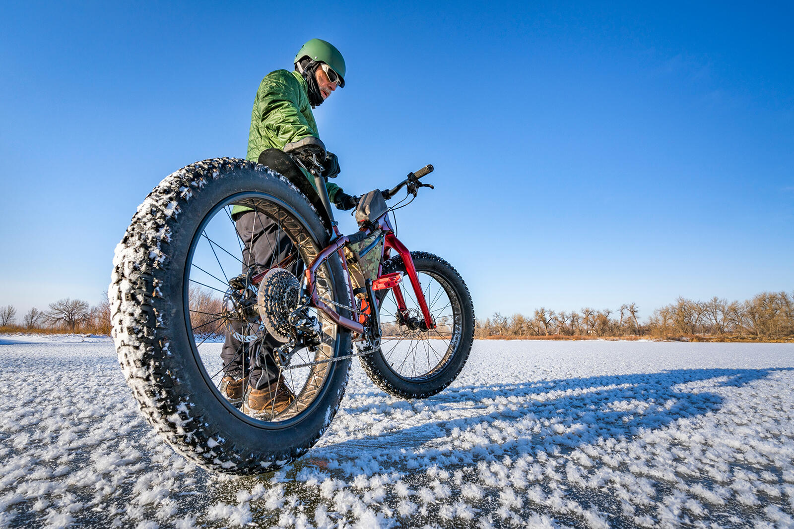 Mężczyzna stojący przy fatbike na zaśnieżonym polu