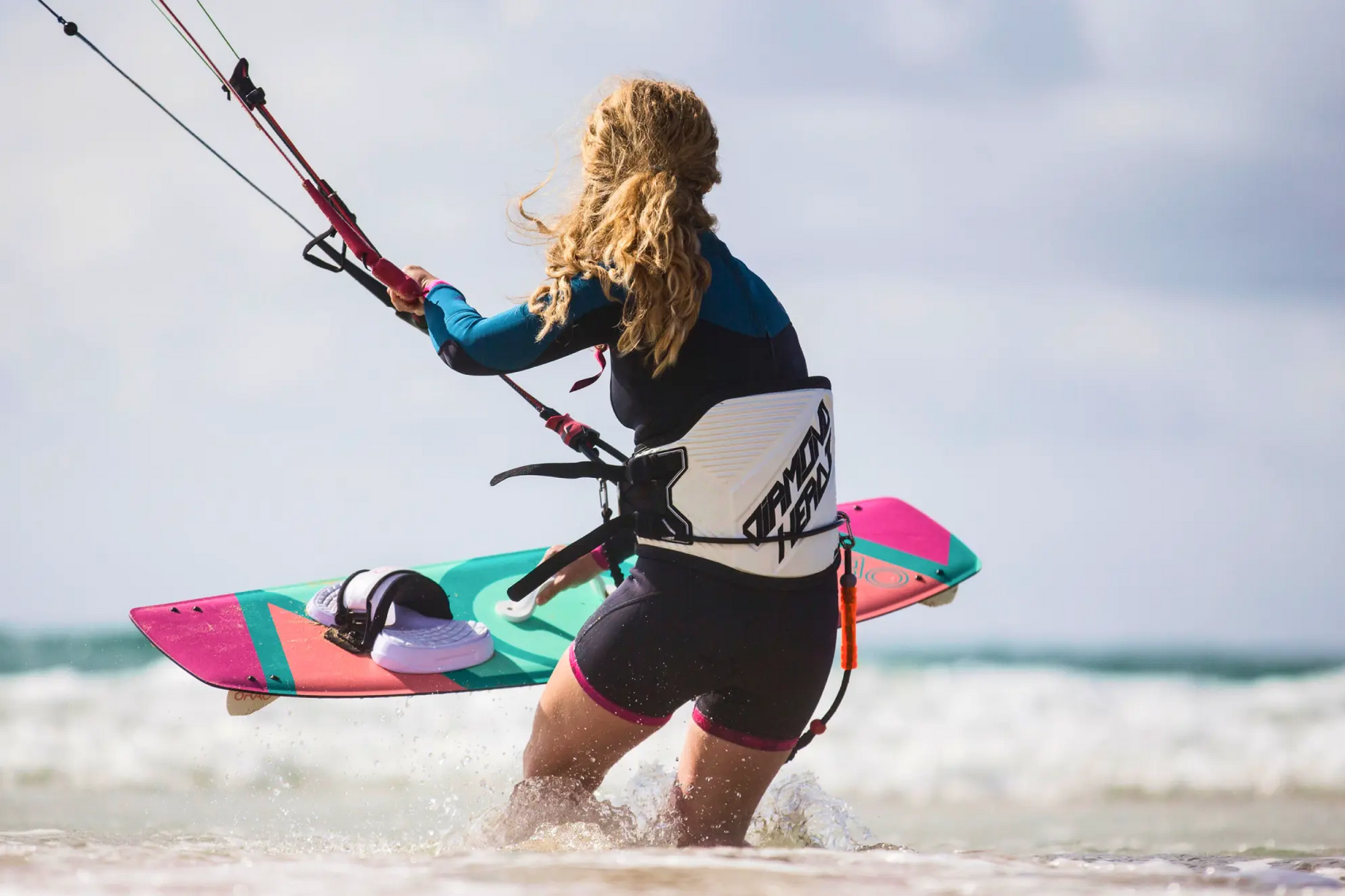 Kobieta w wodzie trzymająca deskę do kitesurfingu