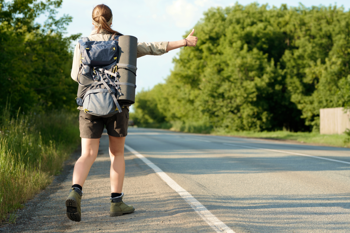 Dziewczyna z plecakiem i karimatą łapiąca stopa