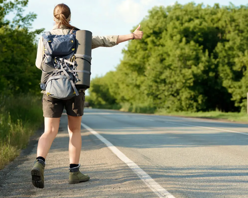 Dziewczyna z plecakiem i karimatą łapiąca stopa