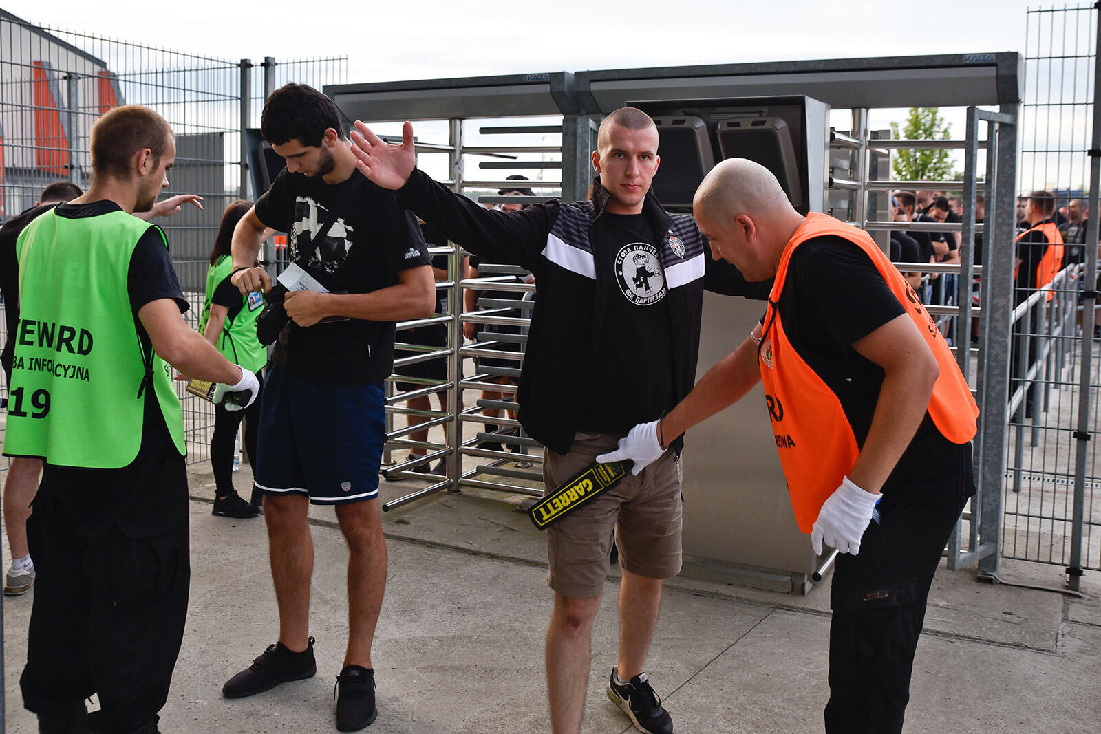 Mężczyźni kontrolowani przez ochroniarzy podczas wejścia na stadion