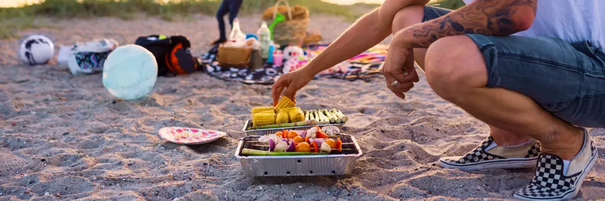 Mężczyzna pilnujący grilla na plaży