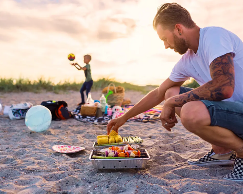 Mężczyzna pilnujący grilla na plaży