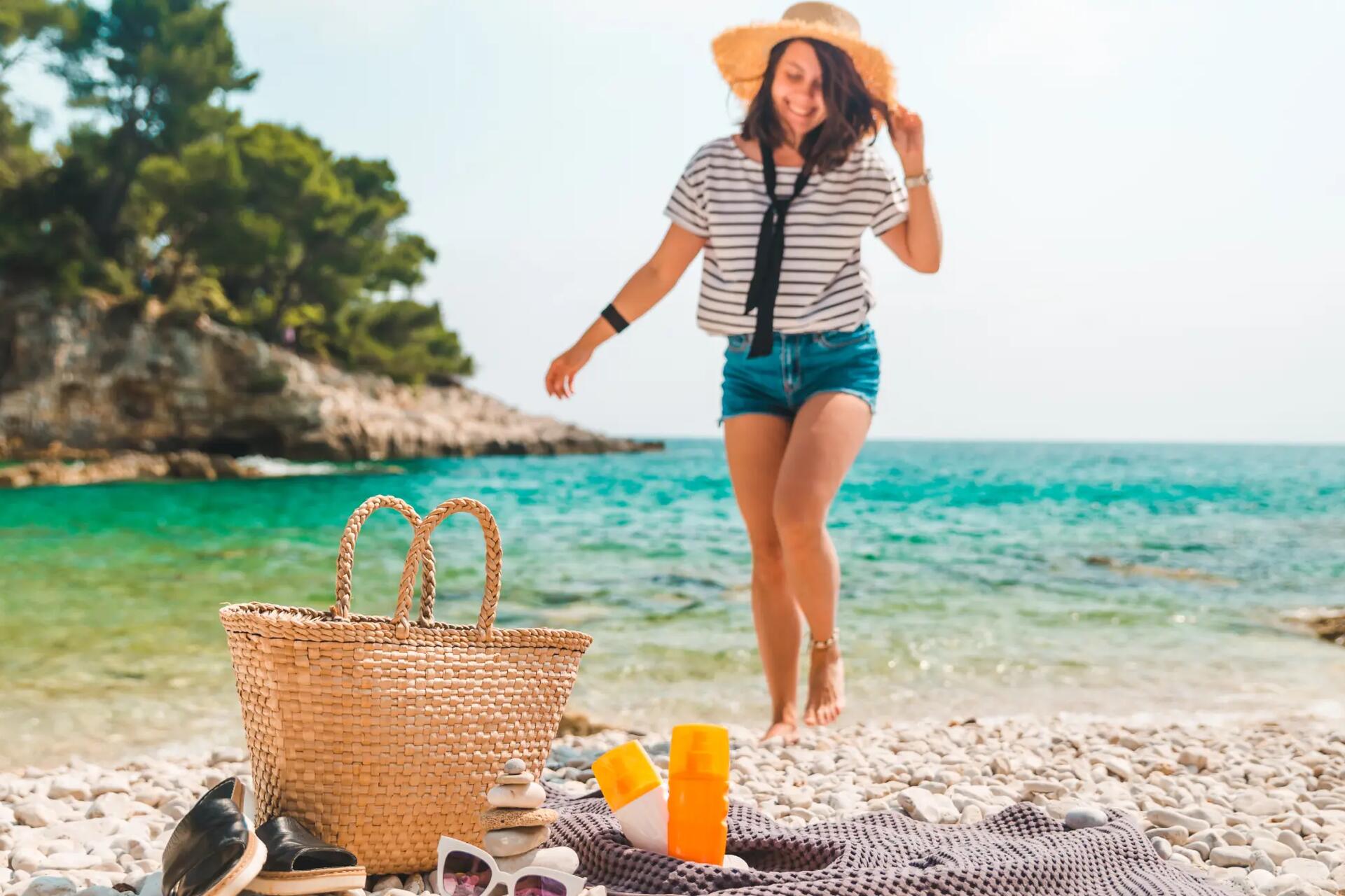 Kobieta w kapeluszu na plaży obok torba i koc