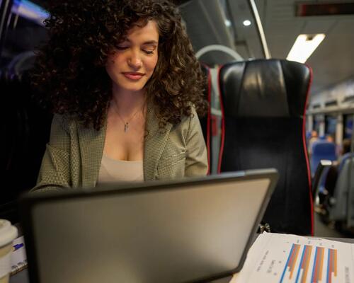Kobieta pracująca na laptopie podróżując pociągiem nocą 